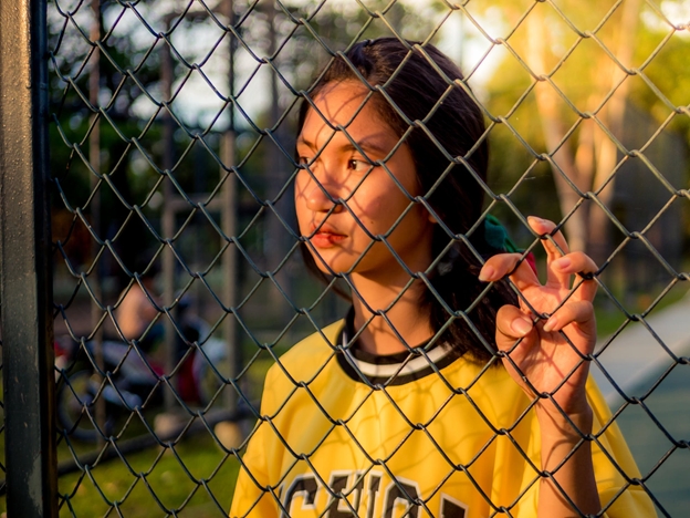 Young Athlete Looking Through Chain Link Fence